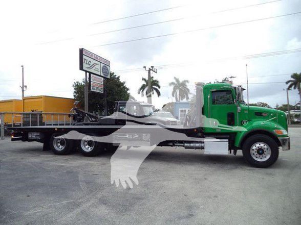 Peterbilt 348 tow truck tractor with a green cab and flatbed trailer.