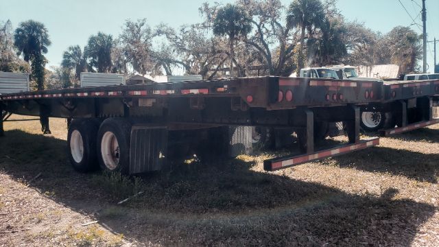 Flatbed trailer in a yard showing dual rear axles and wooden deck; long 53x102 dimension stated implicitly by title.