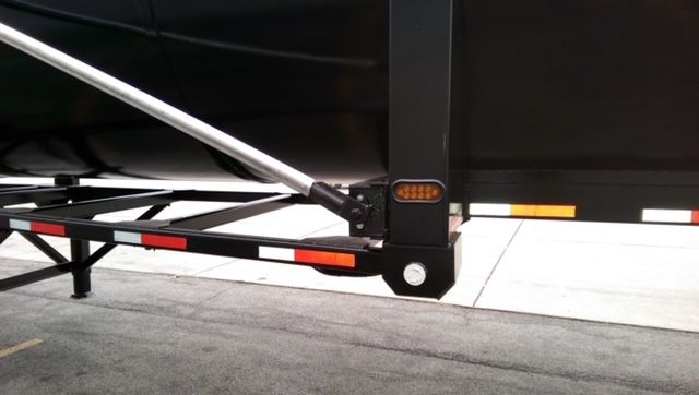 Bottom corner of a Great Dane dump trailer showing black frame, support leg, and round bottom with reflective strips.
