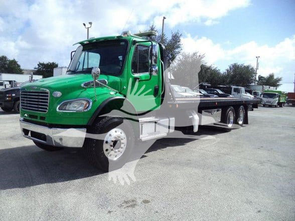 Green Freightliner Business Class M2 106 tow truck with flatbed. Vehicle shows front cab, side, and rear dual axles. Visible text includes none clearly legible on badges due to distance.