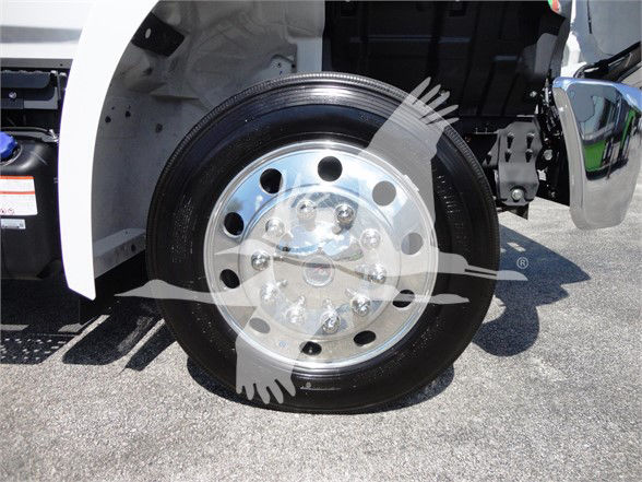 Wheel and front fender area of a 2022 Hino 268A tow truck showing a polished steel wheel with lug nuts and black tire.