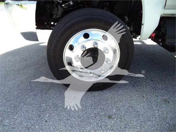 Wheel and tire of a 2023 International CV truck showing front wheel with chrome hub and lug nuts, part of a tow truck configuration.