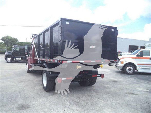 Rear of Freightliner BUSINESS CLASS M2 106 dump truck with black cargo container and graphic bird silhouette.