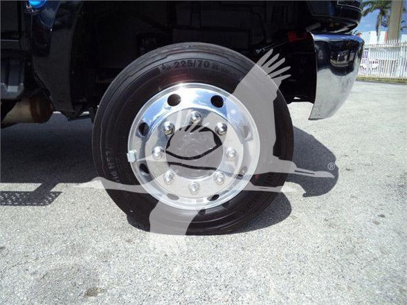Wheel and tire close-up on a black truck, chrome hubcap with multiple lug nuts and tire size 225/70 R19.5 visible.