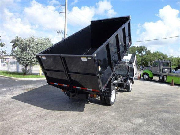Isuzu NPR HD dump truck with a raised black dump bed, rear view showing the hydraulic lift and cargo area.
