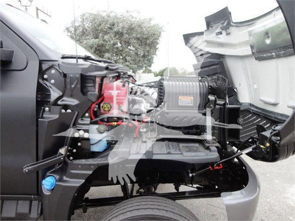 Trucks engine bay showing battery, air intake, and hydraulic components in a compact cab-over design.