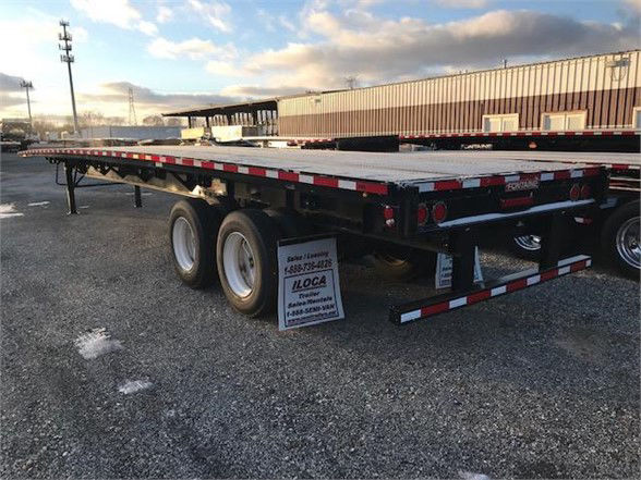 Flatbed trailer with dual rear axles and red/white reflective tape, Fontaine VELOCITY steel model in a lot.