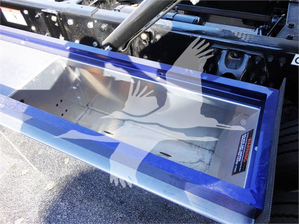 Tow truck storage box mounted on truck frame with blue and silver painted edges and a metal interior.