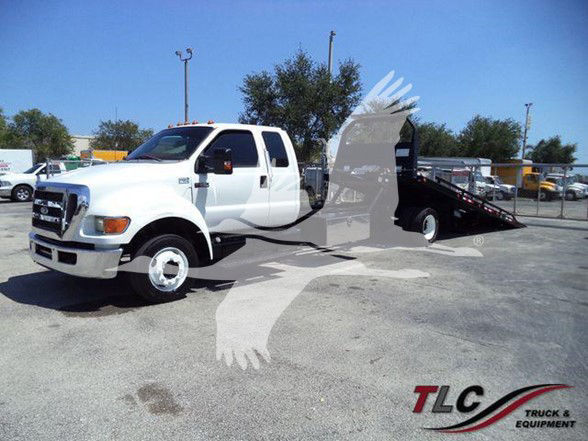 2015 Ford F650 XLT tow truck in a lot with brightness, white cab and black tow bed