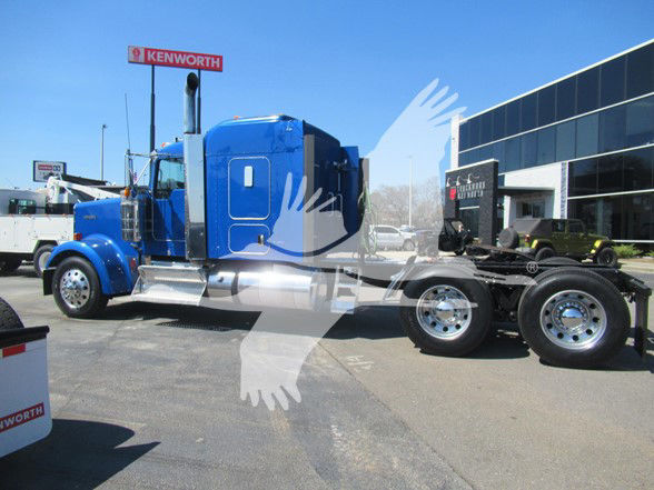 Blue 2018 Kenworth W900L semi-truck tractor parked outside dealership, long tractor with sleeper cab and dual rear axles.