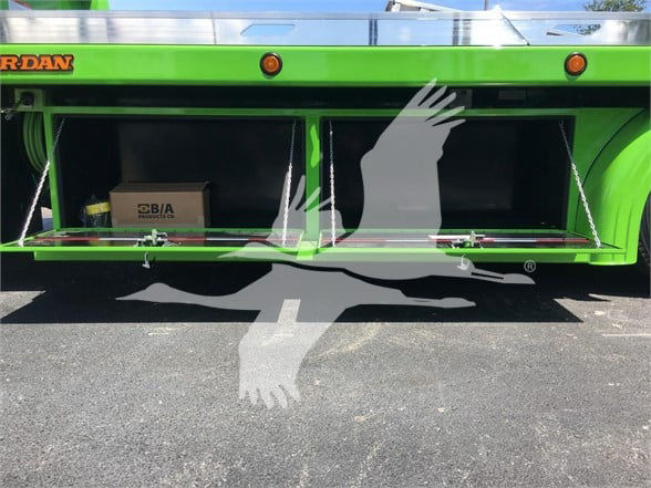 Green Peterbilt 337 truck with open storage compartments showing cardboard box and equipment inside.