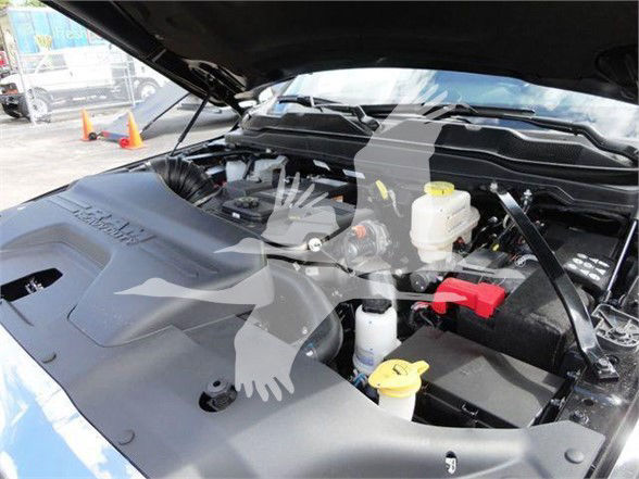 Ram engine bay with hood open; visible labels include coolant reservoir caps, brake fluid reservoir, engine components; no legible model text clearly readable due to watermark overlay.