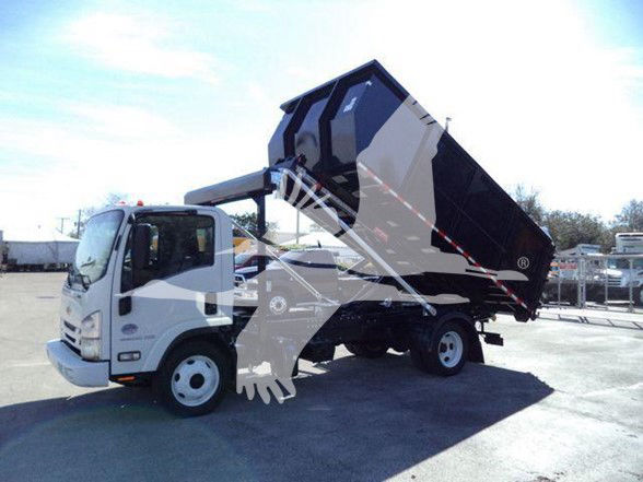 Isuzu NRR dump truck in raised bed configuration ready for dumping. cab visible with bucket seat, side mirrors, and hydraulic lifting mechanism.