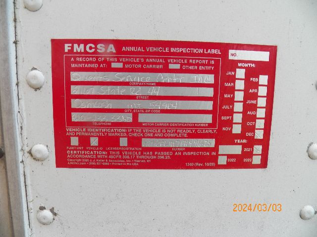 FMCSA annual vehicle inspection label on a white door; red label with white text and checkboxes; fields for company name, street, city, state, ZIP, motor carrier number, and inspection dates; yellow date stamp 2024/03/03 at bottom right.