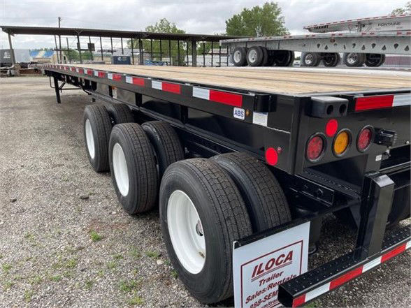 Fontaine XCALIBUR extendable flatbed trailer showing three axles and rear lighting, with ILCOA trailer tag and ABS sticker.