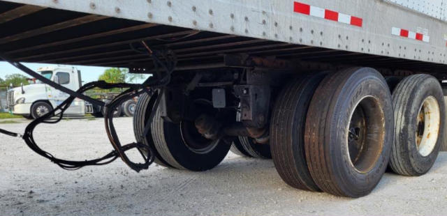 Trailer undercarriage with axles and tires. Visible: dual rear axles with tires, wiring harness, and undercarriage framework.