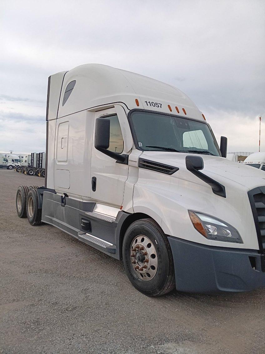 Truck cab of a white 2021 Freightliner Cascadia 126 with sleeper, front angle showing windshield, side mirror, and dual rear axles; number 11057 on top of cab.