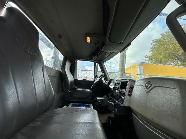 Truck cab interior showing driver and passenger seats with dashboard, steering wheel, and overhead console.