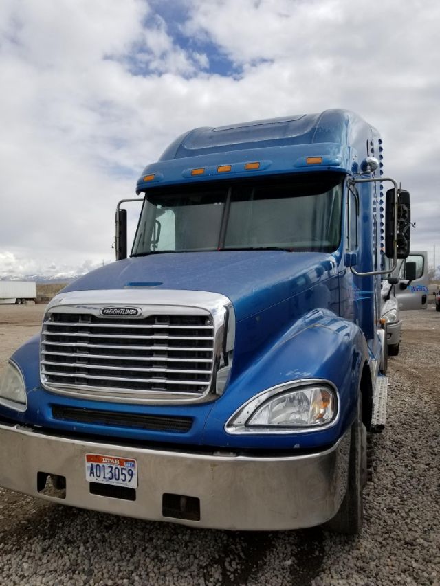 Front view of a blue Freightliner Columbia truck with chrome grille, large headlights, and Utah license plate in foreground.