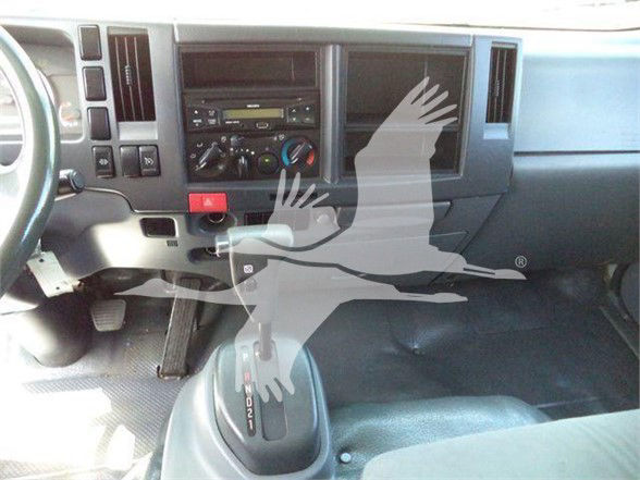 Isuzu NRR truck interior dashboard with manual gear shifter and climate controls visible.