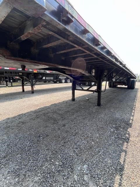 Flatbed trailer undercarriage and legs visible showing steel beams and support jacks.