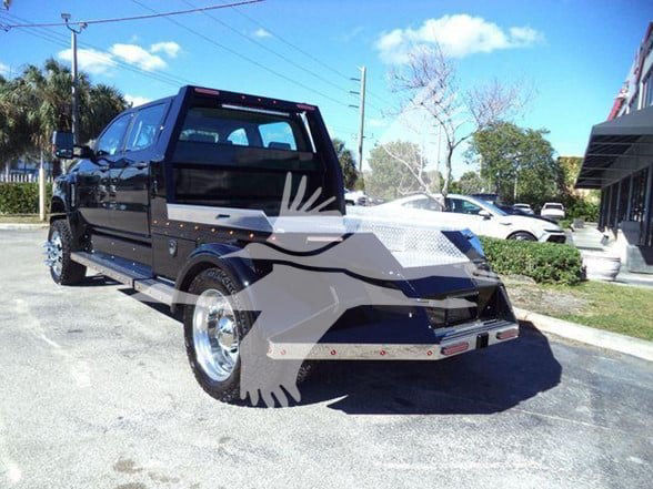 Heavy hauler black 2023 International CV truck with custom armored bumper and wide chrome wheels, side steps, and extended cab.