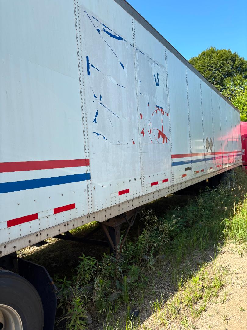 Trailer side of a 2016 International Prostar conventional sleeper truck with white exterior, blue and red stripes, and visible riveted panels.