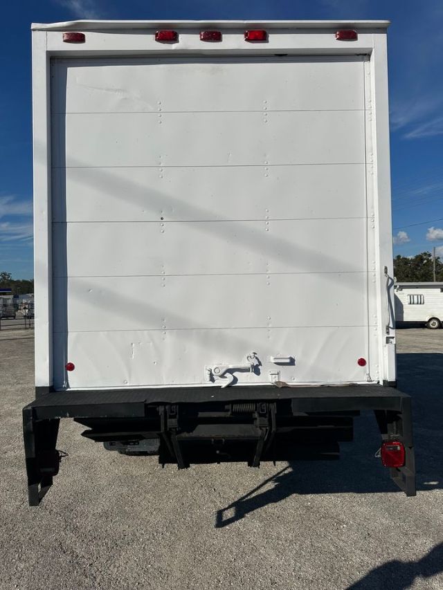 Rear view of a white box truck with a raised cargo door, red tail lights, and a black hitch area.