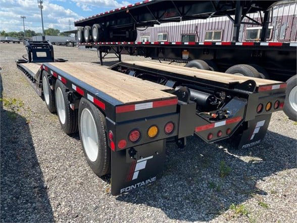 Fontaine 55 ton steel roller paver lowboy trailer showing 24ft deck with dual rear axles and wooden deck, dark gray/black finish, Fontaine branding on mudflaps.