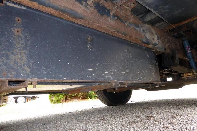 Underbody view of a 2005 Bluebird All American school bus showing a rusty chassis frame and underside hardware.