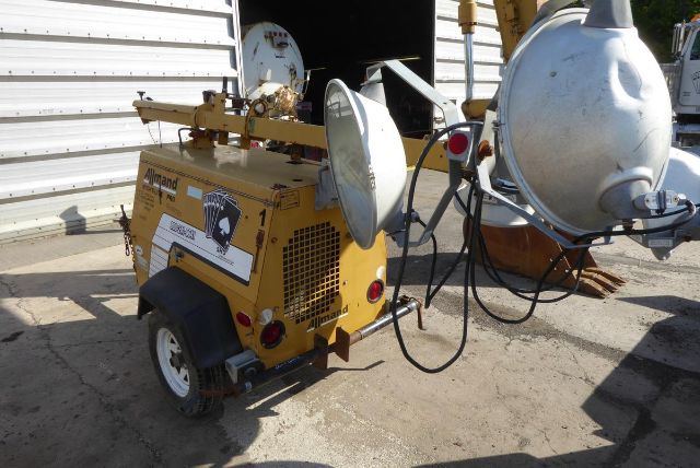 Allmand Night Lite Pro light tower unit with yellow engine housing, two large reflector lamps, and cables. Side label visible on panel with text and logo.