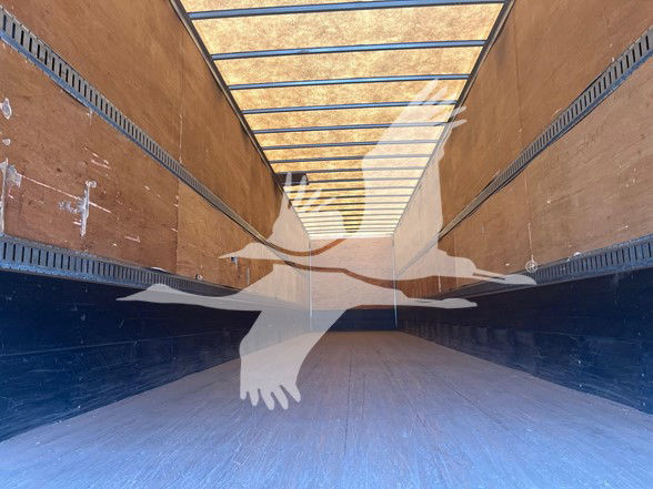 Van trailer interior showing empty cargo space with wooden side walls and overhead tracks.