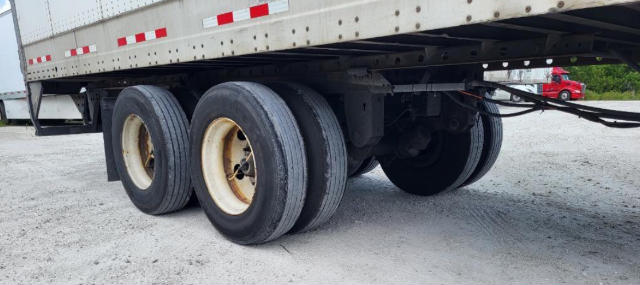 Trailer axle assembly with dual rear tires under a Vanguard VXP trailer showing wheel rims and suspension components.