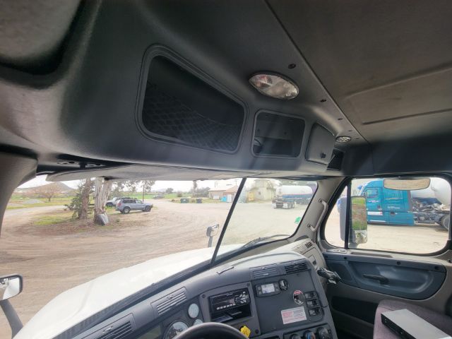 Freightliner Cascadia truck interior showing overhead storage and dashboard area. Visible text on dashboard panels not legible.