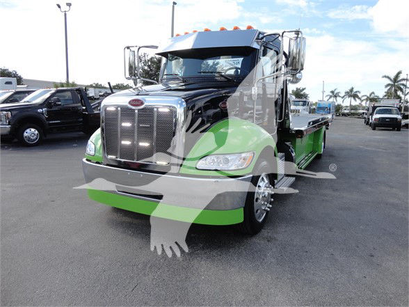 Peterbilt 337 tow truck in black and green livery, front grille, chrome bumper, side mirrors, and flatbed visible.