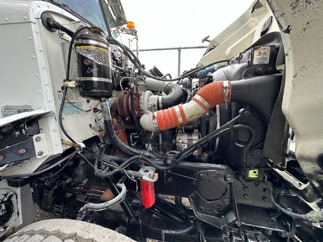 Peterbilt vacuum truck engine bay showing air filter canister, turbocharger, hoses, coolant lines, and various components in front section.
