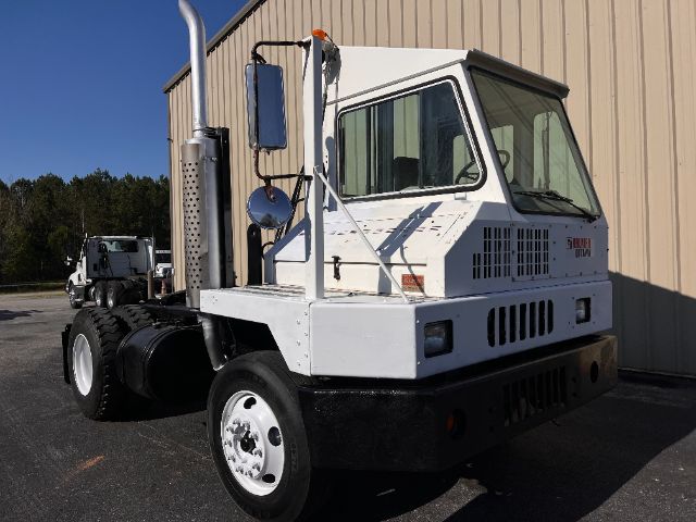 Kalmar Ottawa 30 yard truck, white cab, side view showing exhaust stack, grille, and windshield with orange beacon on top.