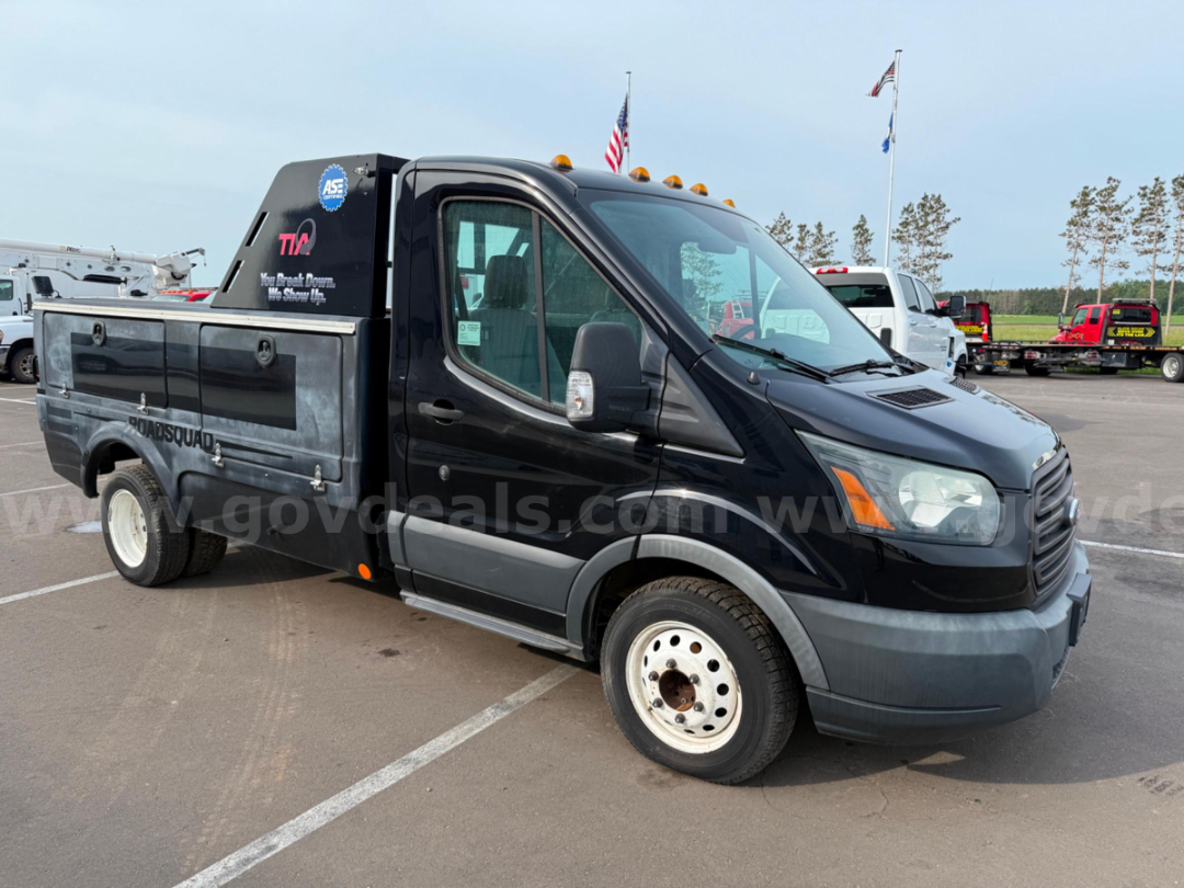 Ford Transit commercial utility van in service/utility category with black cab and utility bed, side stickers, and front wheel visible.
