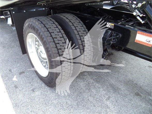 Dual rear wheels on Kenworth truck chassis with wheel wells visible and a warning label on the frame.