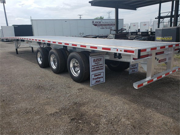 All-aluminum Fontaine Revolution 52 trailer with tri-axle dual tandem wheels, side rails, rear ramp, and reflective safety tape. Text visible includes ILOCA signs and trailer branding.