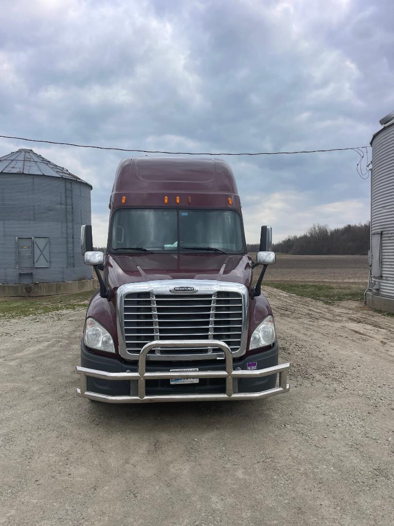 Front view of a maroon 2014 Freightliner Cascadia 125 sleeper truck with chrome grille guard, large windshield, and side mirrors.