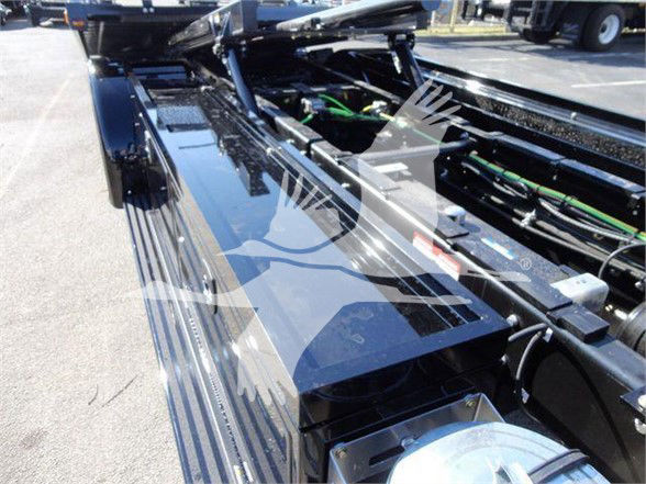 Truck chassis frame with hydraulic/battery cables and components visible; close-up of frame rail and wiring harnesses.