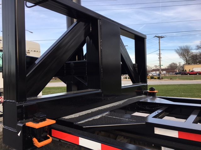 Wabash tipper trailer chassis frame with black paint, structural steel beams, orange latch/pin, and reflective red/white striping.
