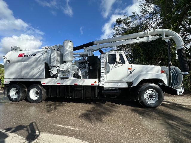 Rear-view of a white 2000 International F-2554 vacuum truck with a large cylindrical vacuum tank and overhead piping system.