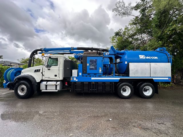 2017 Mack GU713 vacuum truck side view showing blue vacuum tank and hoses attached to white cab