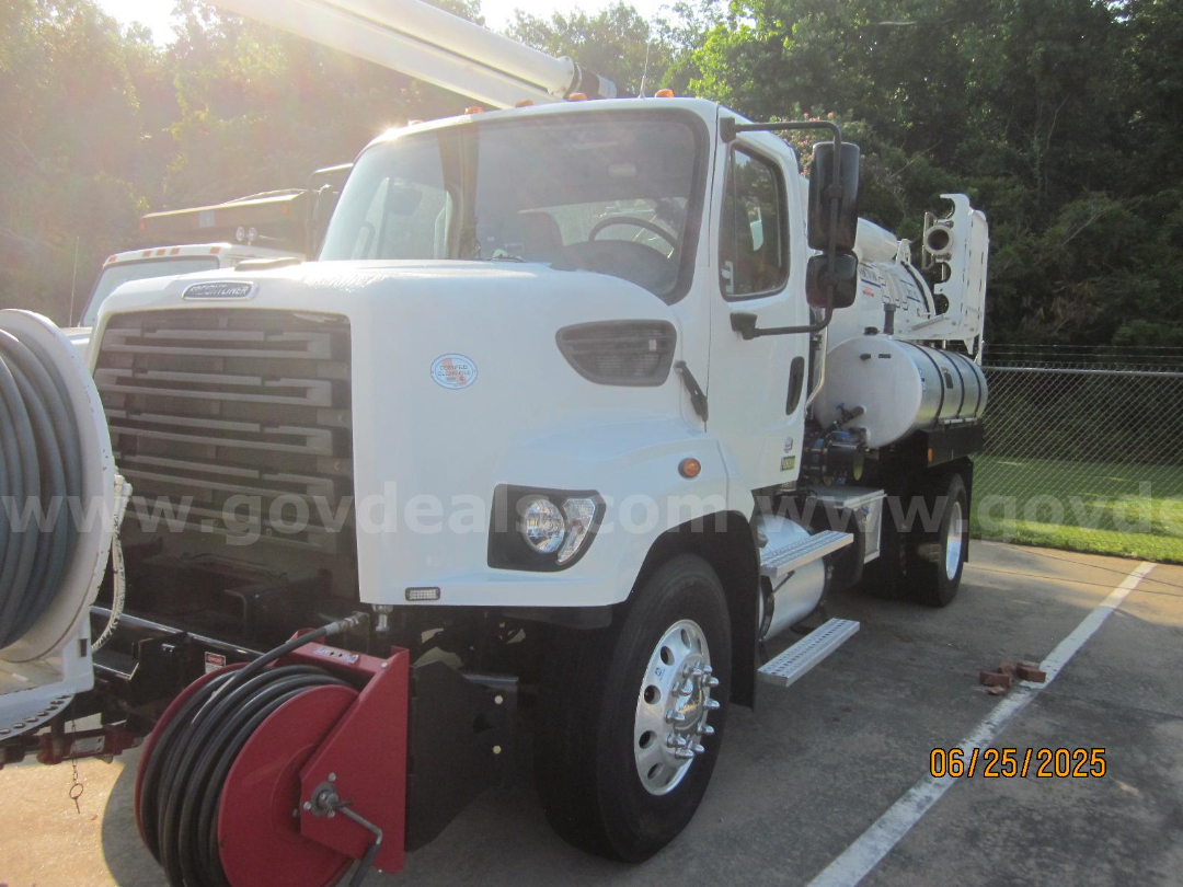 Front-left view of a white 2017 Freightliner Vactor vacuum truck showing cab, large front grille, side steps, and hose reels mounted behind cab.