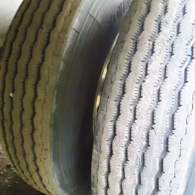 Two truck tires stacked with visible treads in a trailer wheel area.