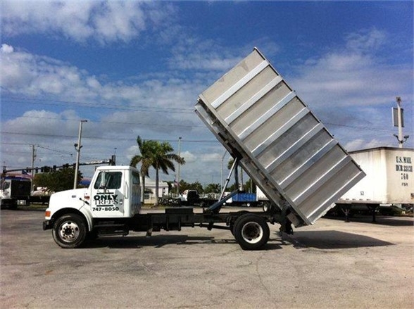 Truck with a raised dump bed crane on a hitch in a lot, aluminum dump body.