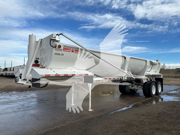 Ranco 34' half round steel rock end dump trailer with high lift gate, white with red decals, dual rear axles, parked on gravel.