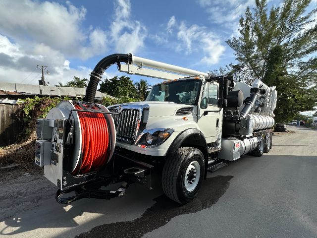 2014 International 7500 vacuum truck with large red hose reel mounted at the front and vacuum hose extending overhead.